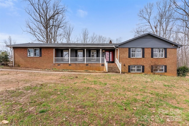 view of front of property featuring brick siding, a porch, a chimney, and a front lawn