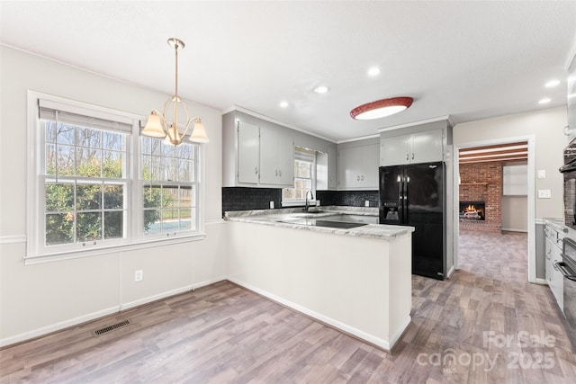 822 Bethlehem Rd, Kings Mountain, NC 28086 - kitchen featuring black appliances, a brick fireplace, a peninsula, light wood-style flooring, and recessed lighting