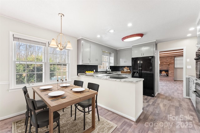 822 Bethlehem Rd, Kings Mountain, NC 28086 - kitchen with black appliances, a peninsula, a brick fireplace, light wood-style floors, and recessed lighting