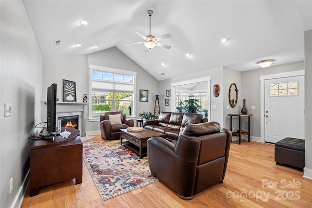 living room with light wood-style flooring, baseboards, a ceiling fan, and a premium fireplace