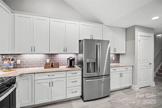 kitchen with backsplash, white cabinets, lofted ceiling, and stainless steel fridge with ice dispenser