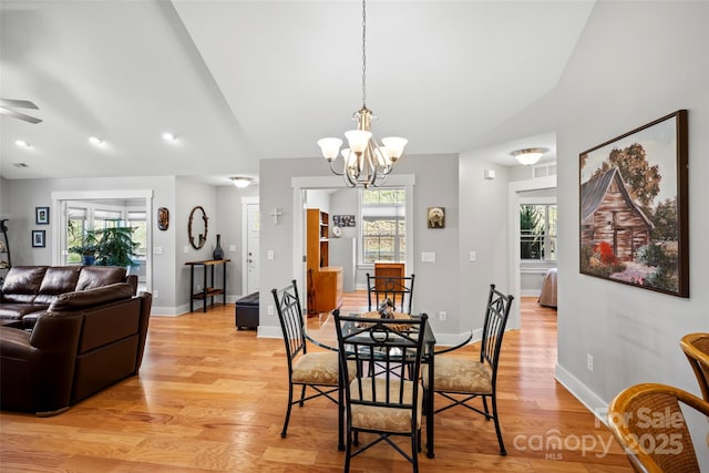 dining room featuring ceiling fan with notable chandelier, vaulted ceiling, light wood-style floors, and baseboards