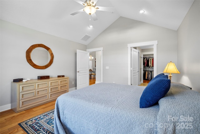 bedroom featuring visible vents, a walk in closet, light wood-style flooring, baseboards, and ceiling fan