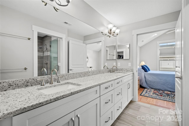 ensuite bathroom featuring a sink, visible vents, a stall shower, and vaulted ceiling