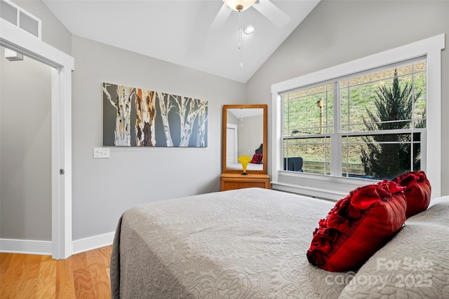 bedroom with visible vents, a ceiling fan, wood finished floors, baseboards, and vaulted ceiling