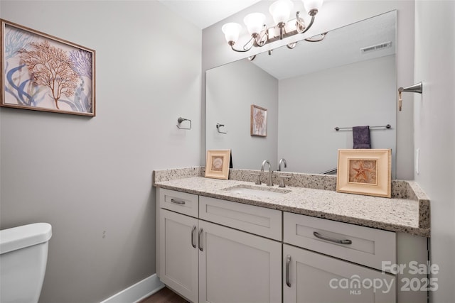 bathroom with visible vents, toilet, baseboards, a chandelier, and vanity