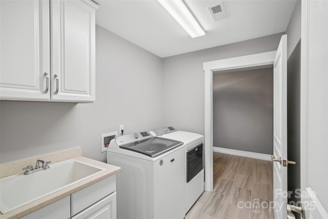 laundry room featuring baseboards, visible vents, cabinet space, a sink, and washer and dryer