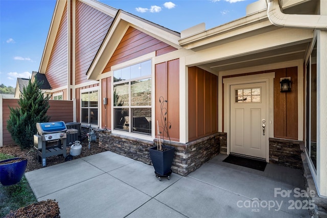 entrance to property featuring fence and stone siding