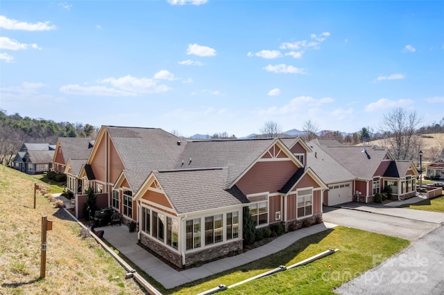 view of front of home with a residential view, stone siding, roof with shingles, and driveway