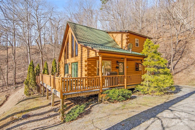 view of front of house with log siding, covered porch, and metal roof