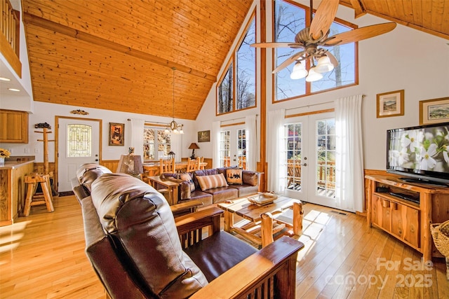 living room featuring lofted ceiling, light wood-style flooring, wood ceiling, french doors, and ceiling fan with notable chandelier