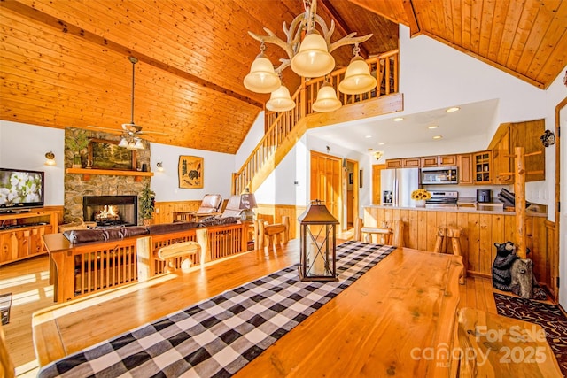 dining room with wood ceiling, light wood-style flooring, stairs, and ceiling fan with notable chandelier