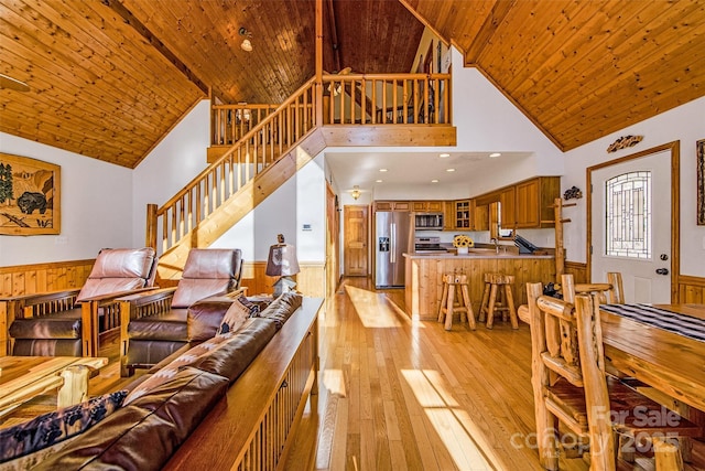 living area with stairs, light wood-style floors, wooden ceiling, and wainscoting