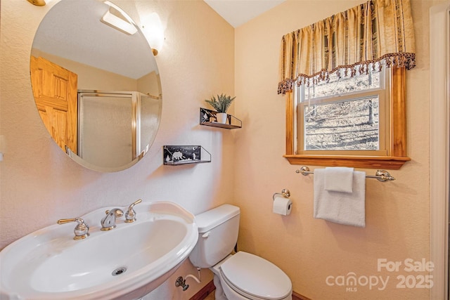 full bathroom featuring a stall shower, toilet, and a sink