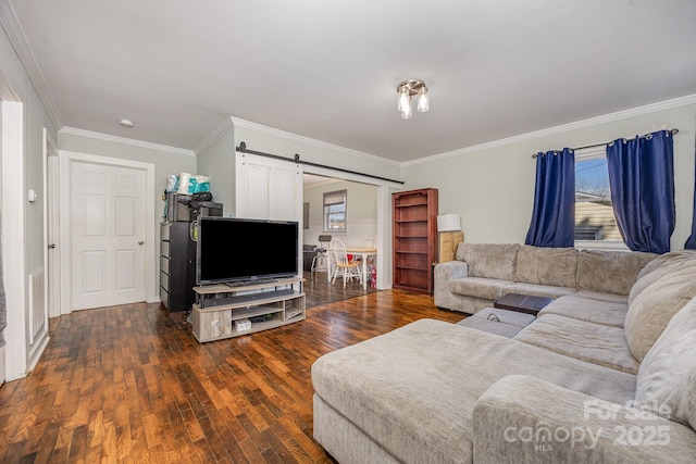 living room with a wealth of natural light, a barn door, wood-type flooring, and ornamental molding