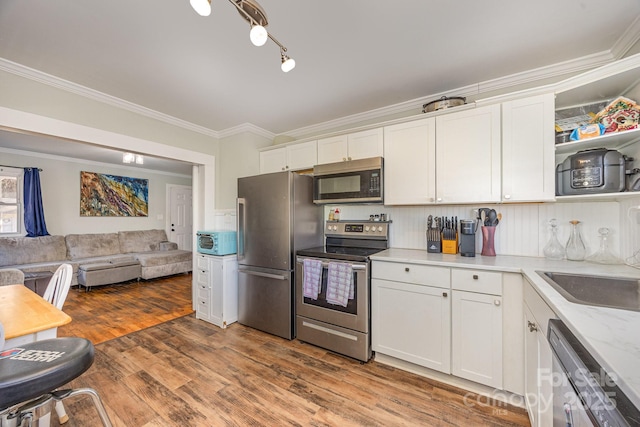 kitchen featuring a sink, appliances with stainless steel finishes, open floor plan, and white cabinets