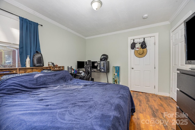 bedroom with wood finished floors, baseboards, and ornamental molding