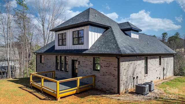 back of property with brick siding, a lawn, board and batten siding, and roof with shingles