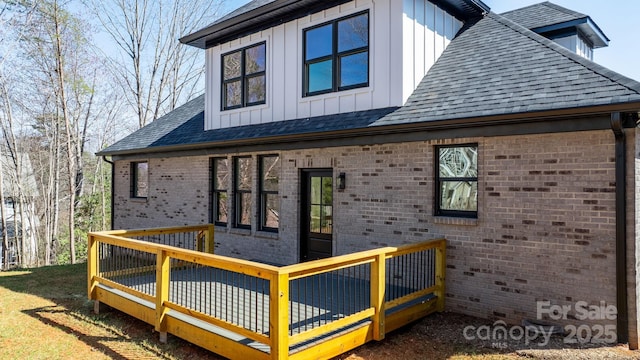 exterior space with board and batten siding, a deck, and a shingled roof