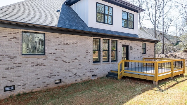 exterior space featuring brick siding, board and batten siding, a wooden deck, roof with shingles, and crawl space