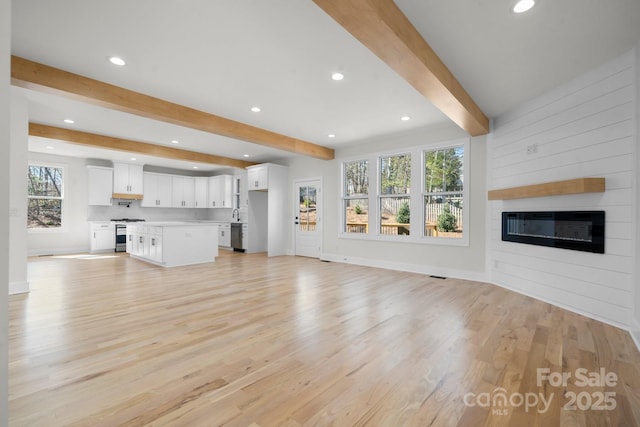 unfurnished living room featuring baseboards, light wood finished floors, beam ceiling, recessed lighting, and a fireplace