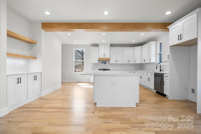 kitchen featuring beamed ceiling, light wood-style flooring, light countertops, and stainless steel dishwasher