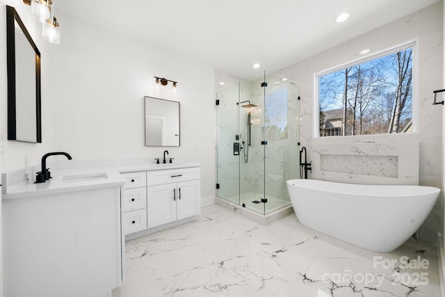 bathroom featuring a freestanding bath, marble finish floor, a marble finish shower, and a sink