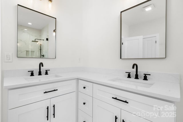 bathroom featuring a marble finish shower, double vanity, and a sink