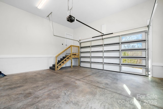 garage with a garage door opener and concrete block wall