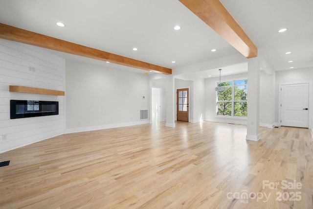 unfurnished living room with visible vents, beam ceiling, light wood-style flooring, a fireplace, and recessed lighting