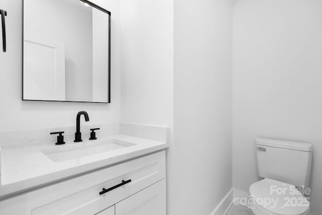 bathroom featuring vanity, toilet, and baseboards