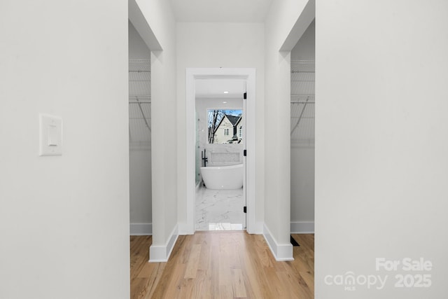 corridor with baseboards and light wood-style floors