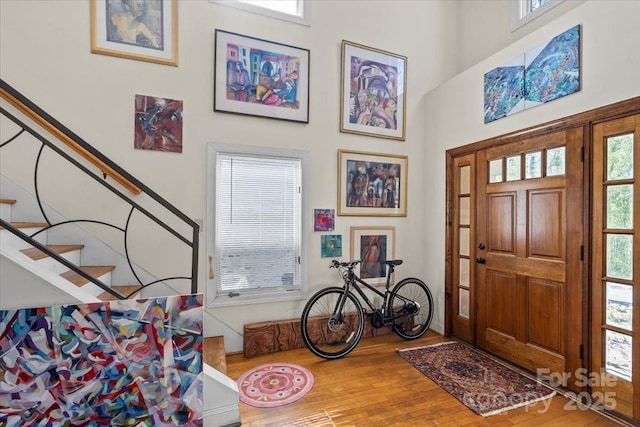 entrance foyer featuring a high ceiling, wood finished floors, and stairs