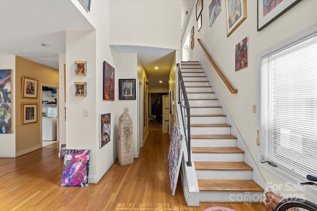 stairway featuring baseboards, wood finished floors, and a towering ceiling