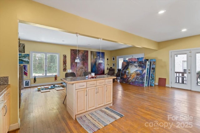 kitchen featuring hardwood / wood-style floors, baseboards, light brown cabinetry, french doors, and open floor plan