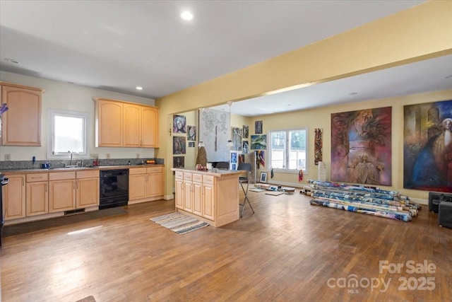 kitchen featuring light brown cabinets, a sink, black dishwasher, light wood-style floors, and open floor plan