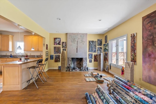 living room featuring recessed lighting, a fireplace, baseboards, and wood finished floors