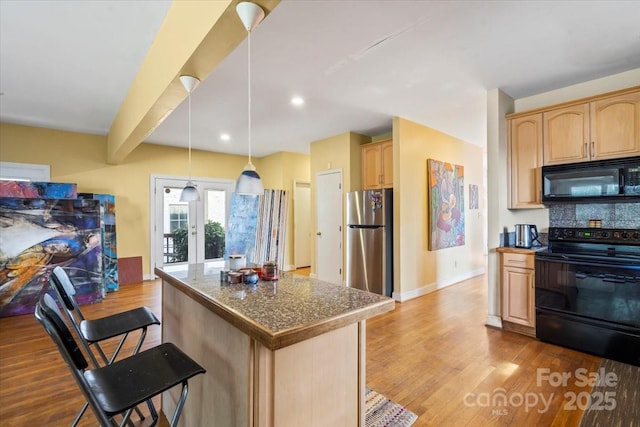 kitchen featuring light brown cabinetry, black appliances, a kitchen bar, and wood finished floors