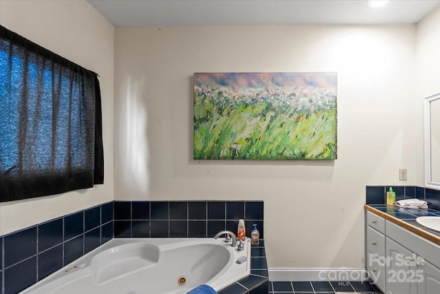 bathroom with a jetted tub, vanity, and baseboards