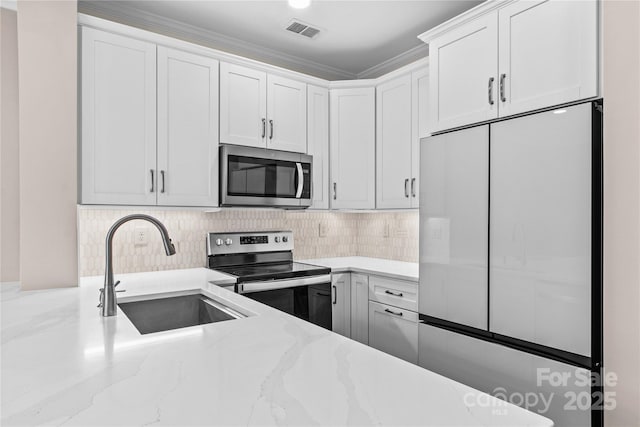 kitchen with light stone counters, visible vents, a sink, white cabinets, and appliances with stainless steel finishes