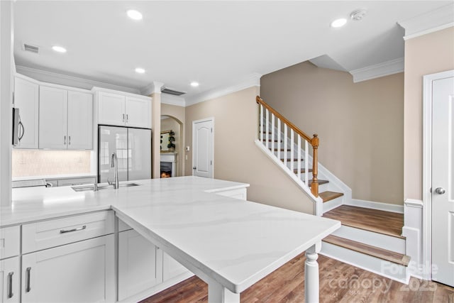 kitchen with visible vents, a sink, wood finished floors, stainless steel appliances, and crown molding