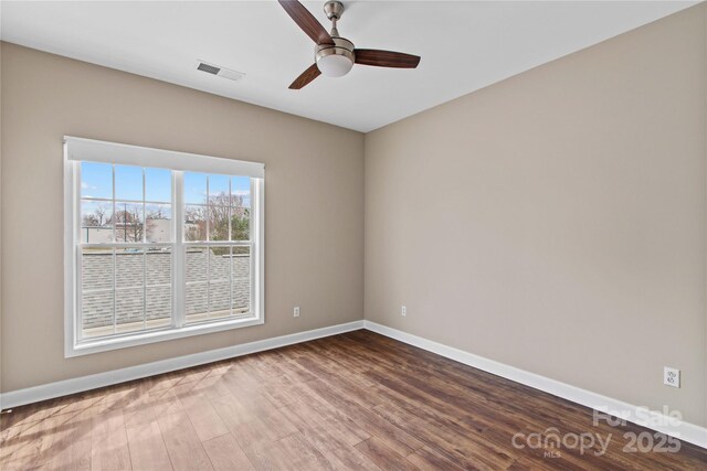 spare room featuring wood finished floors, baseboards, visible vents, and ceiling fan