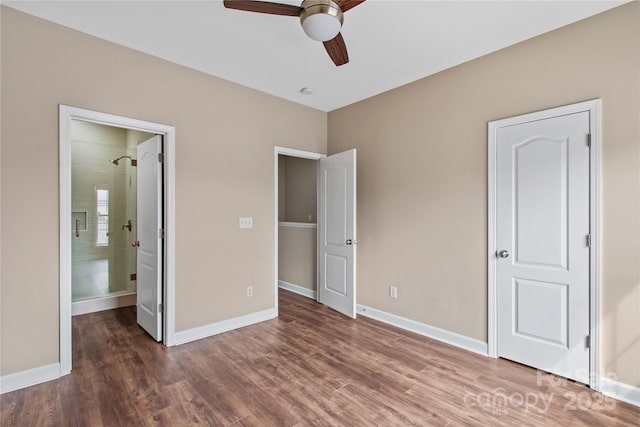 unfurnished bedroom featuring ceiling fan, wood finished floors, baseboards, and connected bathroom