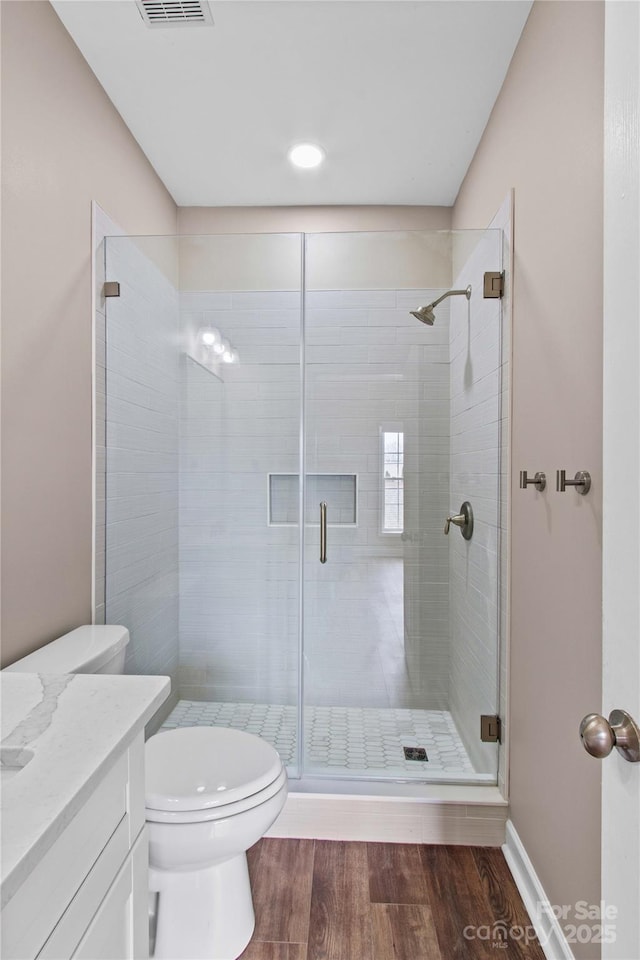 full bath with visible vents, a shower stall, toilet, wood finished floors, and vanity