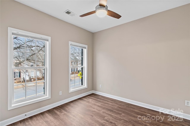 empty room with visible vents, baseboards, dark wood-style flooring, and ceiling fan