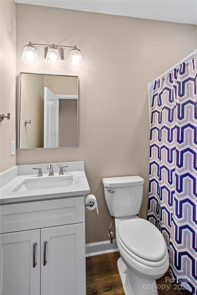 bathroom featuring a shower with curtain, toilet, wood finished floors, baseboards, and vanity