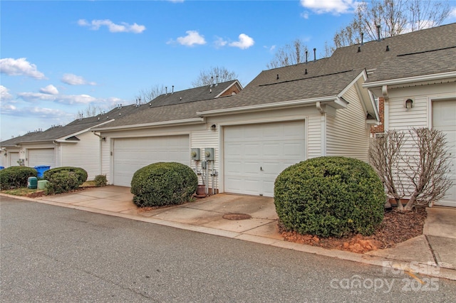 view of side of home featuring a garage and a shingled roof