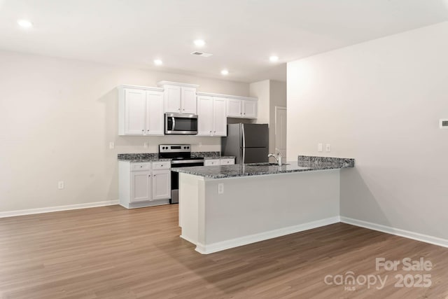 kitchen with light wood finished floors, white cabinets, and appliances with stainless steel finishes