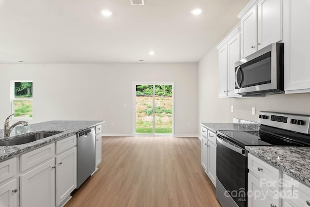 kitchen featuring recessed lighting, a sink, stainless steel appliances, light wood-style floors, and white cabinetry