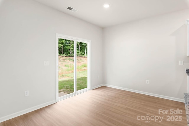 unfurnished room with baseboards, visible vents, and light wood-type flooring